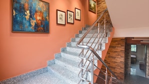 A staircase with a metal handrail, a large abstract painting, and three framed botanical prints on the wall. - Fabhotel Guest O Polis Rajdanga (Kolkata)