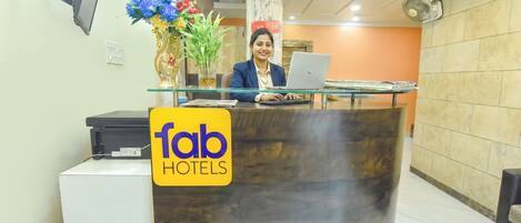 En receptionsdisk med en bärbar dator, en vas med blommor och en skylt med texten ”fantastiska hotell”.
