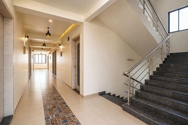 A hotel hallway with a tiled floor, a staircase, and a view of the interior.