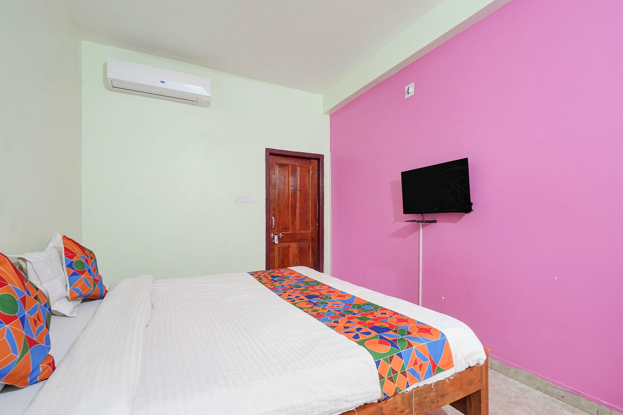 Een slaapkamer met een bed, een aan de muur bevestigde televisie en een airconditioning.