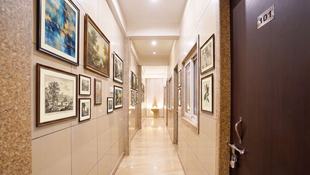 A hallway with framed artwork on the walls, a marble floor, and a door labeled '101'. - FabHotel BlueBell Inn (Lucknow)