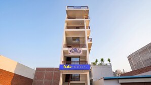 A multi-story hotel with balconies, a staircase, and a sign for 'Bluebell Inn.' - FabHotel BlueBell Inn (Lucknow)