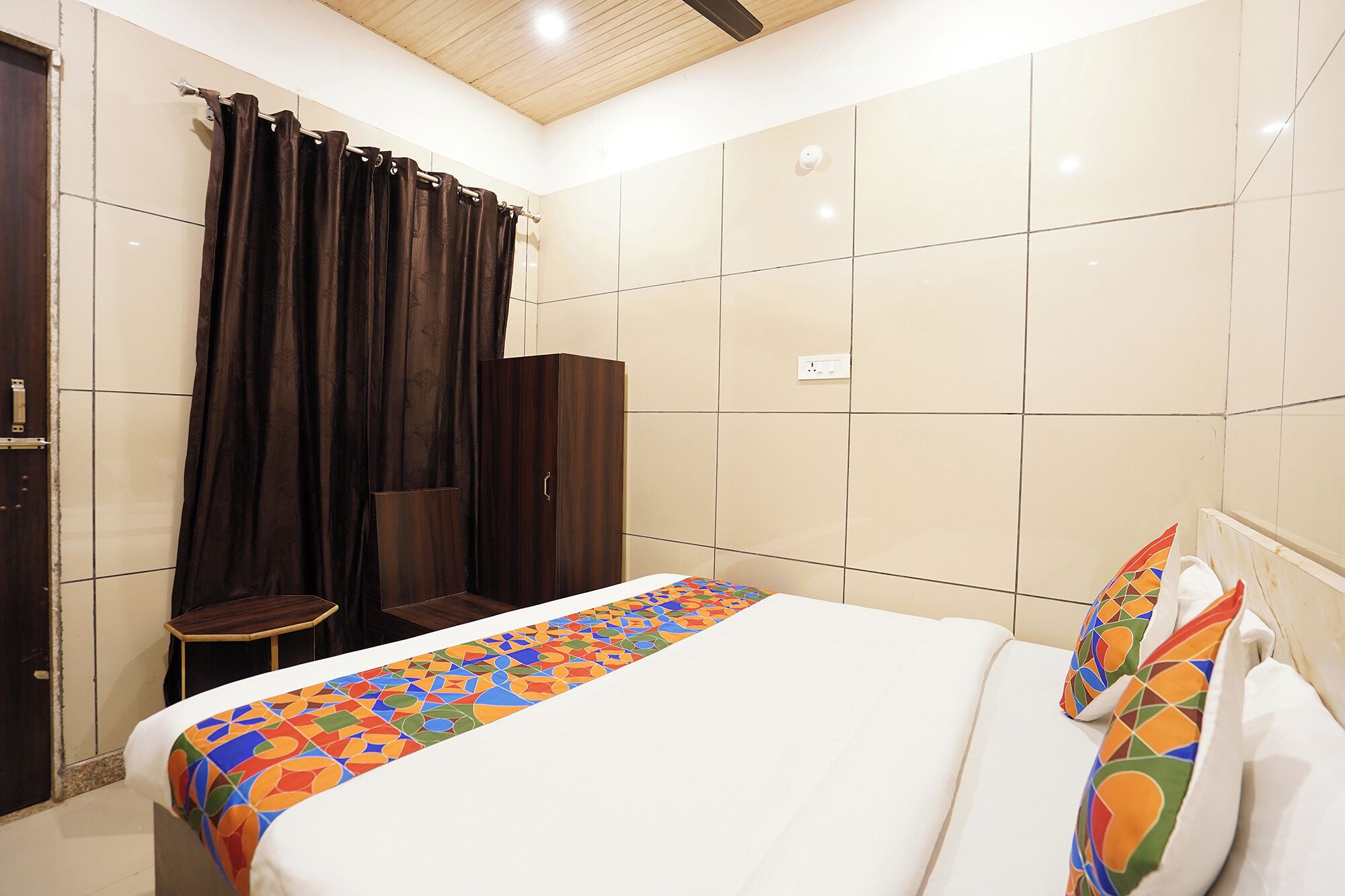 A hotel room with a bed, a small table, a chair, and a wardrobe.