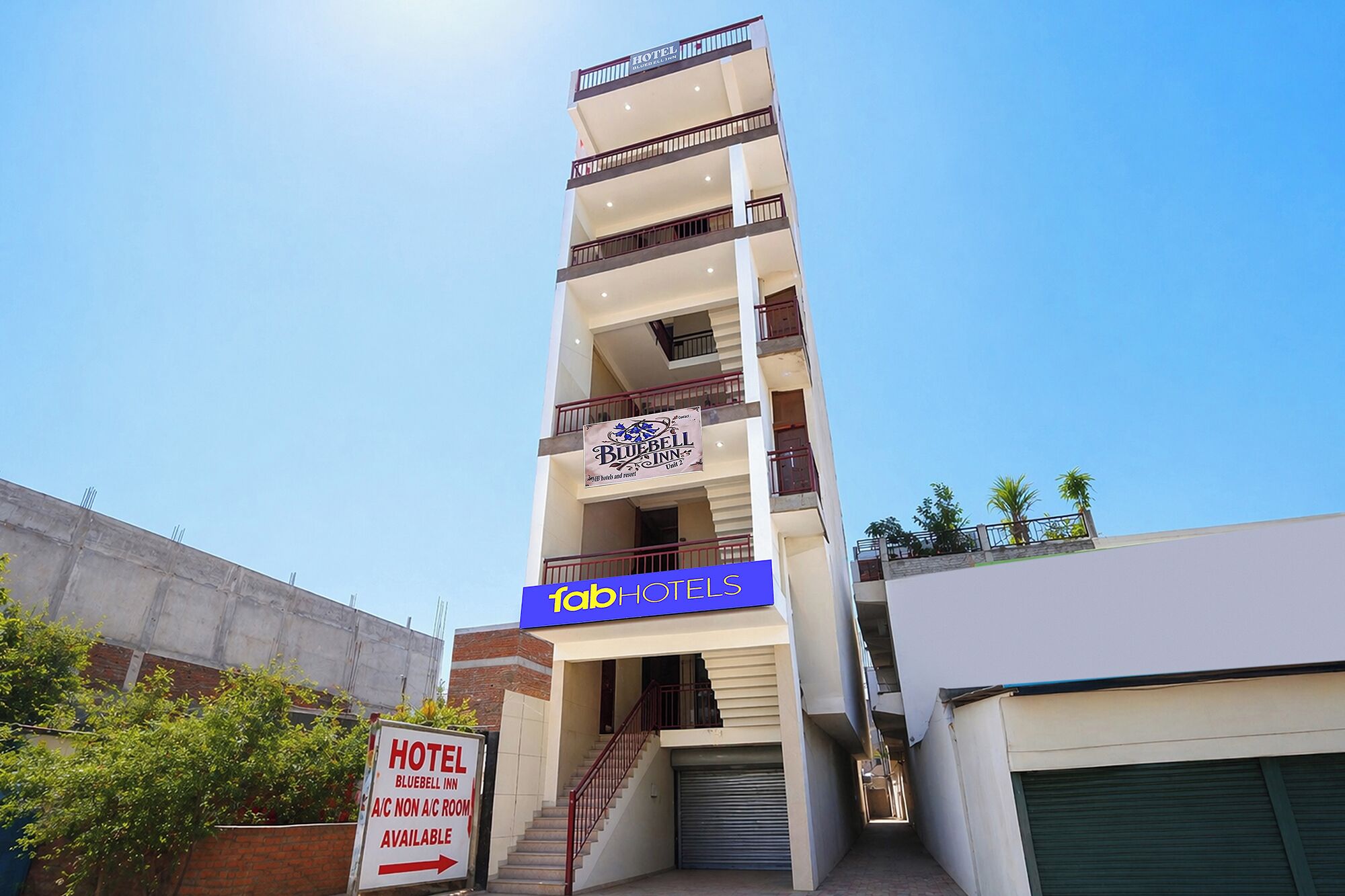 A hotel building with multiple floors, a sign for the Bluebell Inn, and a sign indicating A/C non A/C rooms are available.