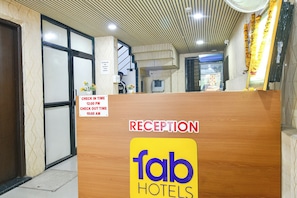 Uma receção com um sinal a indicar horários de entrada e saída, e um sinal para Fab Hotels.