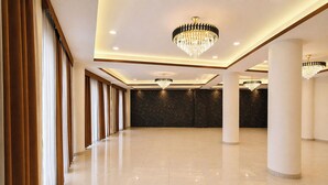 A spacious, well-lit hall with multiple chandeliers, large columns, and a polished floor. - Fabhotel The Muffet (Indore)