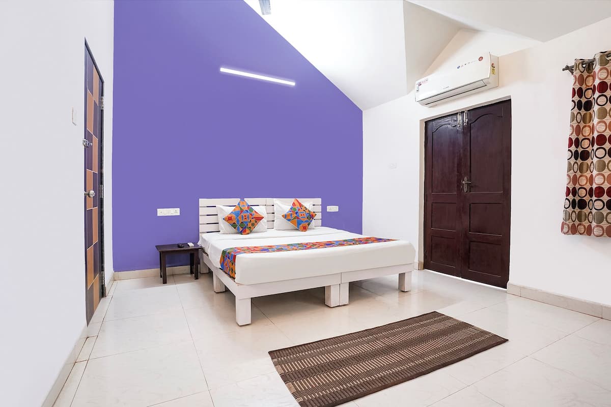 Une chambre à coucher comprenant un lit, une table de chevet, une porte et un climatiseur fixé au mur.