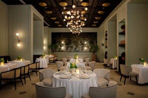 Un restaurante con mesas redondas, manteles blancos y un candelabro.
