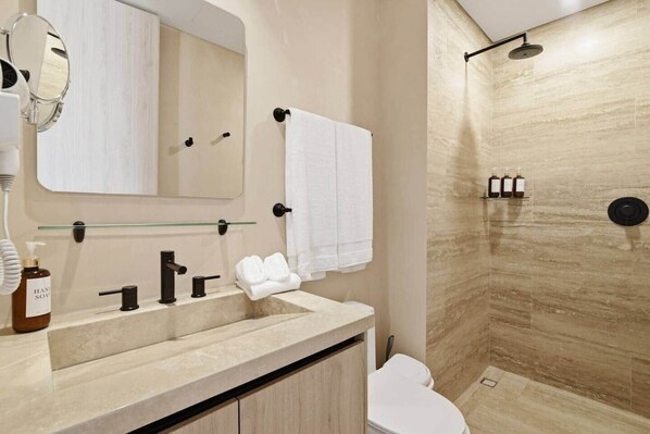 Un baño con lavabo, espejo, toallero y ducha con puerta de cristal.