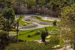 Un campo de golf con búnkeres de arena, obstáculos acuáticos y una valla de madera que delimita el área.