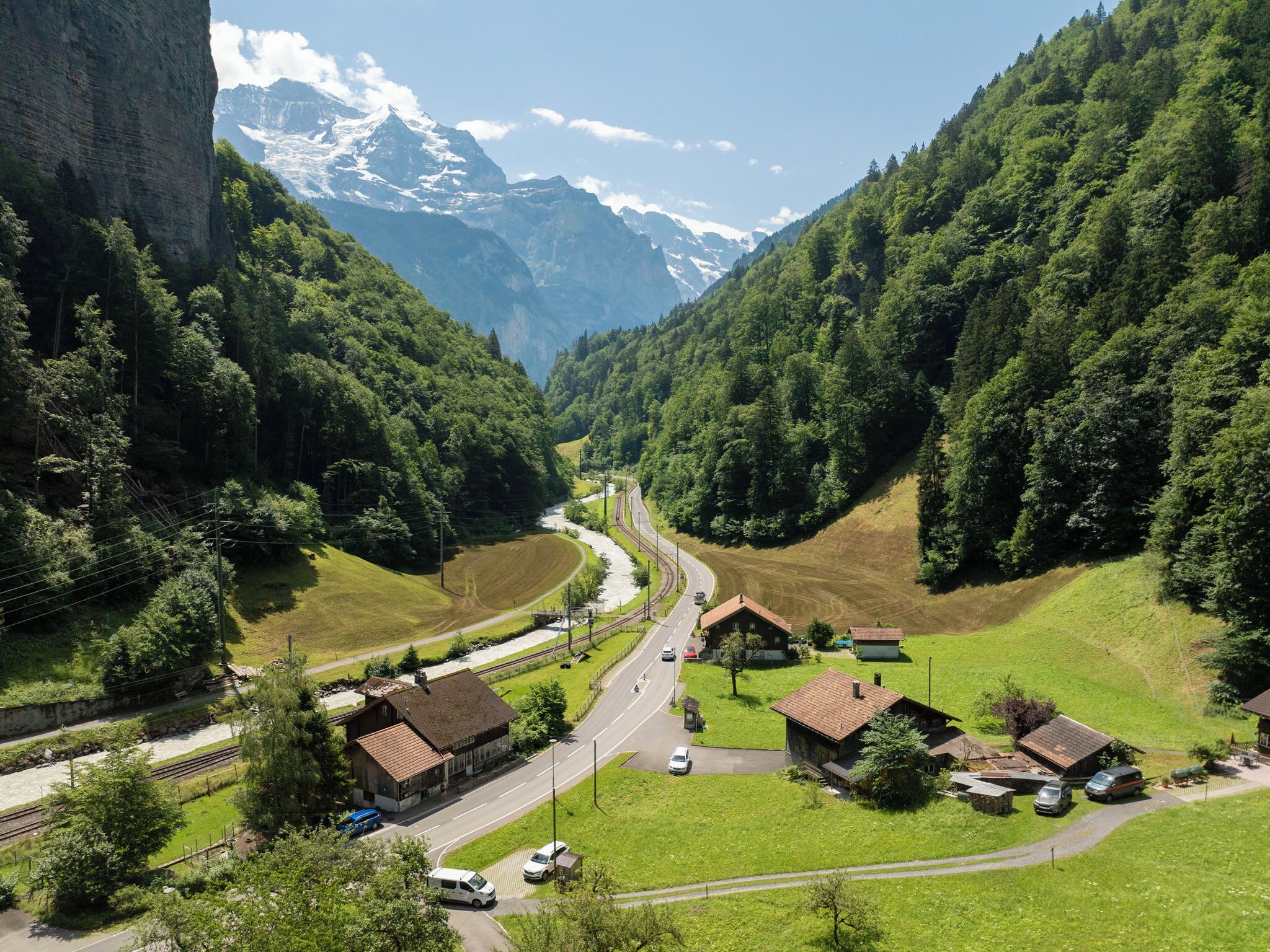 Un valle con una carretera, casas y una montaña al fondo.