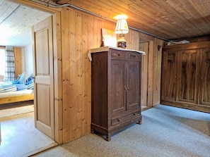 A wooden-paneled room with a bed, a cabinet, and a lamp. - Haus Margrittli by Interhome (Lauterbrunnen)
