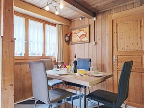 A wooden dining room with a table set for two, chairs, and a painting on the wall. - Haus Margrittli by Interhome (Lauterbrunnen)