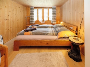 Una habitación de madera con una cama, una mesita y una silla.