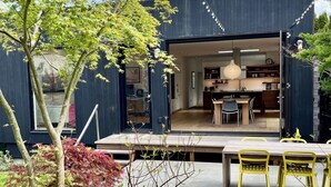 A modern house with a deck, dining area, and visible kitchen. - Wonderful Arboretum 3br custom home w/spectacular outdoor living (Seattle)