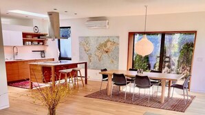 A modern living space with a dining area, kitchen, and large windows. - Wonderful Arboretum 3br custom home w/spectacular outdoor living (Seattle)