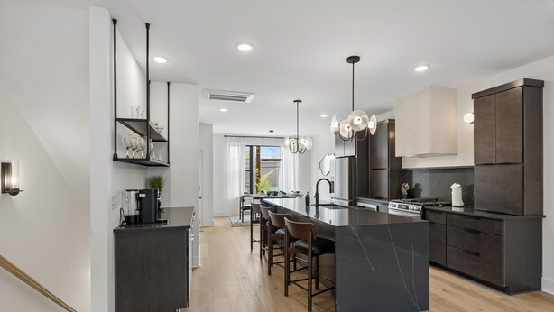 A modern kitchen with a central island, bar stools, and a dining area with a view.