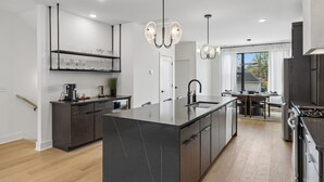 A modern kitchen with a central island, dark cabinetry, and pendant lighting.
