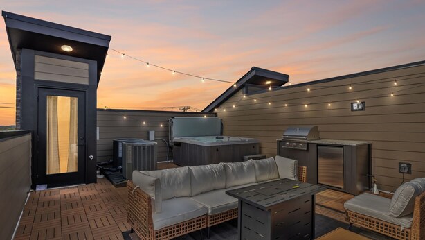 A rooftop patio with a hot tub, grill, and outdoor seating area. - Luxe home w/ rooftop lounge & hottub near downtown (Nashville)