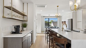A modern kitchen with a central island, bar stools, a coffee machine, and a view to the outside. - Luxe home w/ rooftop lounge & hottub near downtown (Nashville)