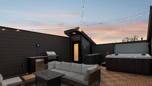 Eine Terrasse im Freien mit Grill, Whirlpool und Sitzgelegenheit.
