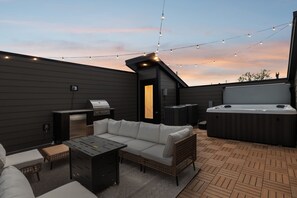 An outdoor patio with a grill, hot tub, and seating area.