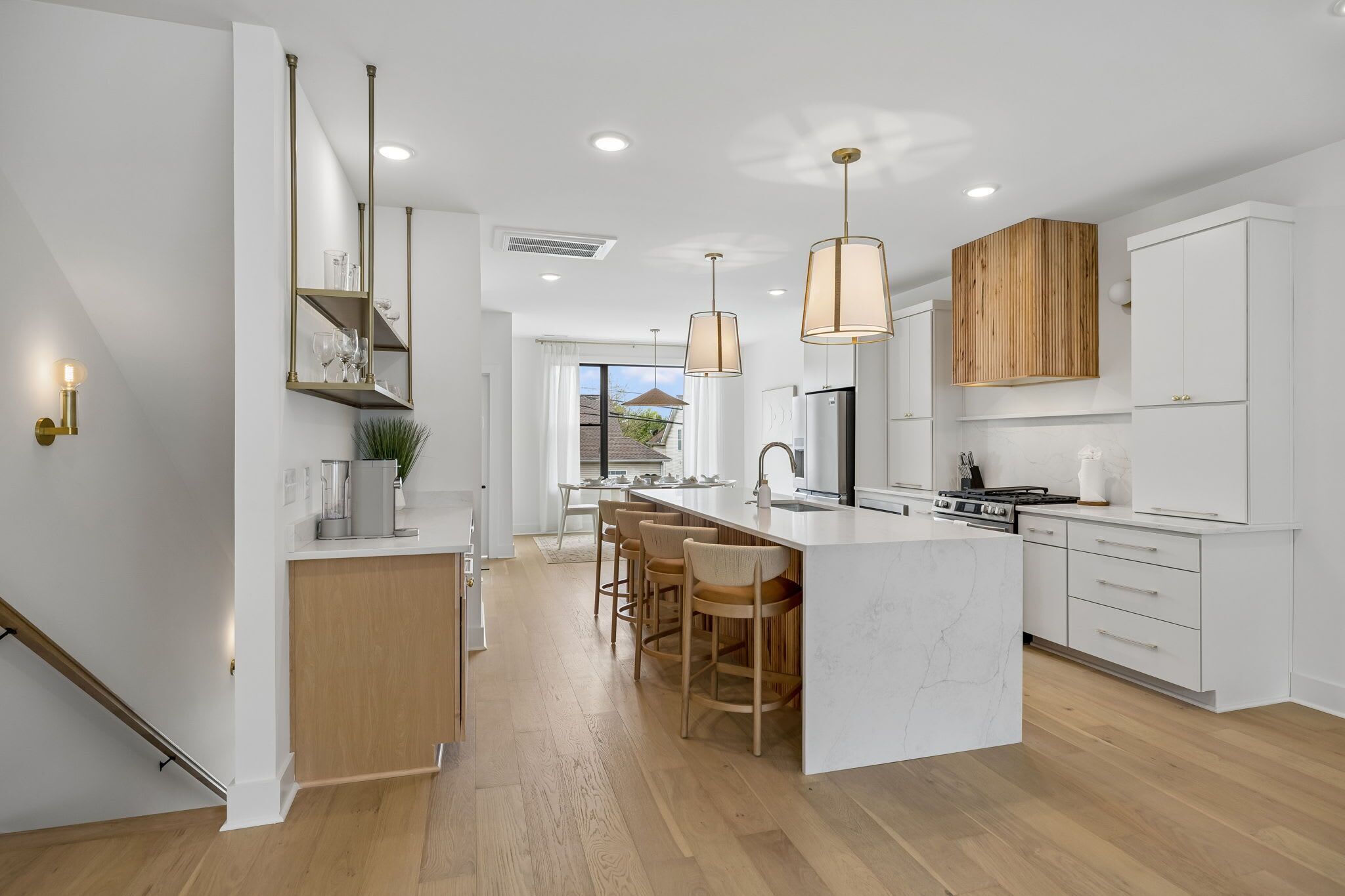 A modern kitchen with a central island, pendant lights, and wooden cabinetry.
