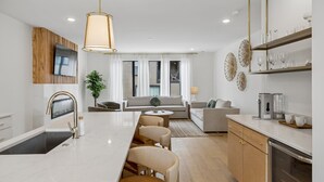 Eine moderne Küche mit Kochinsel, Essbereich und Wohnbereich mit Sofa und Couchtisch.