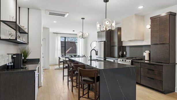 A modern kitchen with a central island, bar stools, a built-in oven, and a large refrigerator. - Upscale home featuring rooftop lounge with hottub! (Nashville)