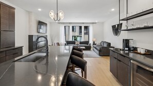 A modern kitchen with a central island, dark cabinetry, and a dining area. - Upscale home featuring rooftop lounge with hottub! (Nashville)