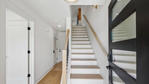 A staircase with wooden steps and a black door with glass panels. - Exclusive townhome ft. rooftop lounge w/ hot tub! (Nashville)