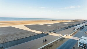 Une promenade en bord de mer avec un chemin piétonnier, un espace de stationnement et un bâtiment portant une enseigne.