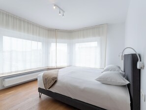 Une chambre moderne avec un grand lit, un radiateur et un luminaire fixé au mur.