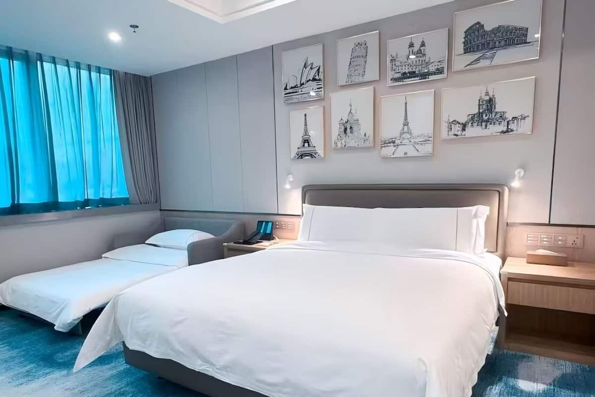 Una habitación de hotel moderna con una cama grande, mesitas de noche, un escritorio y obras de arte en las paredes.