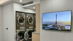 A hotel laundry room with multiple washing machines and a television displaying the Eiffel Tower. - China Mayors Plaza Hotel (Guangzhou)