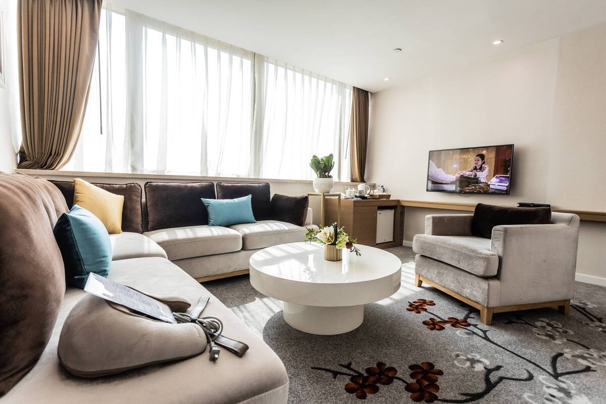 Una sala de estar moderna con un sofá, un sillón, una mesa de centro y un televisor en la pared.