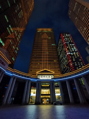 A high-rise building with illuminated lines and a sign in the center. - China Mayors Plaza Hotel (Guangzhou)