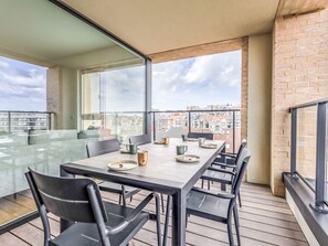 Un balcon moderne avec une table à manger, des chaises et une cloison en verre.