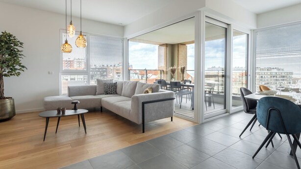A modern living room with a sofa, coffee table, and dining area with chairs. - Parkville with parking & terrace by Interhome (Blankenberge)