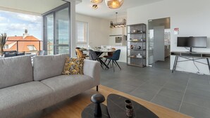A modern living room with a sofa, a coffee table, and a dining area with chairs and a table. - Parkville with parking & terrace by Interhome (Blankenberge)