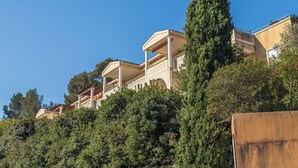 A hillside building with multiple balconies, surrounded by dense greenery and trees. - Domaine de la Luquette by Interhome (Hyères)