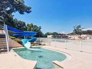 Un espace piscine doté d’un toboggan aquatique bleu et d’une piscine à eau claire.