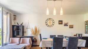 A modern living room with a sofa, dining table, chairs, and a clock on the wall. - Marius Bondil by Interhome (Six Fours)