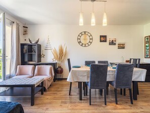 A modern living room with a sofa, dining table, chairs, and a clock on the wall. - Marius Bondil by Interhome (Six Fours)