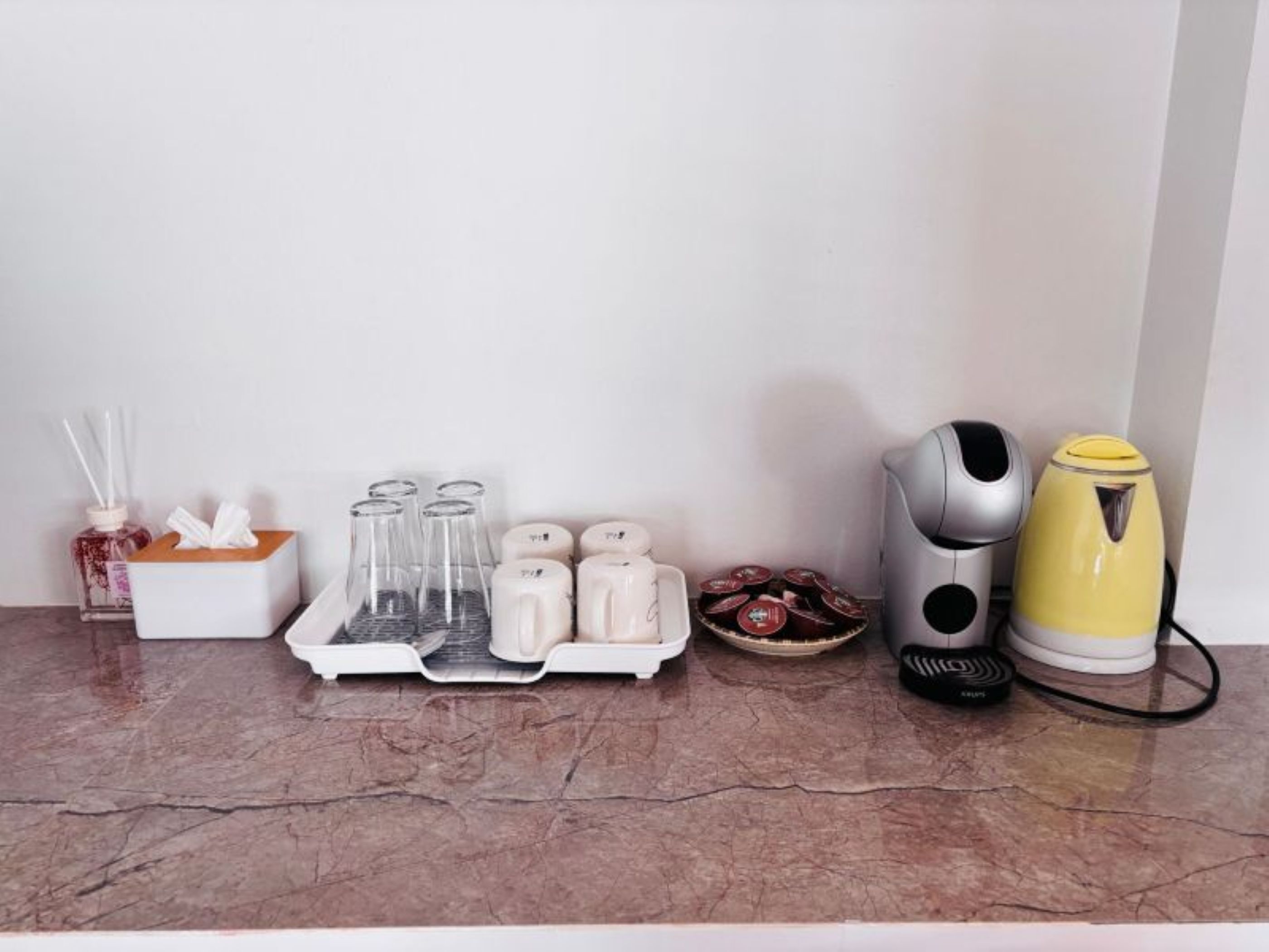 A kitchen counter with a tissue box, glass containers, a tea kettle, and a coffee maker.