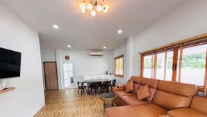 A living room with a sofa, TV, dining table, and chairs. - Villa Ao Nang Krabi with a free car (Krabi)