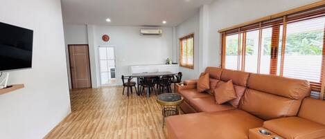 A living room with a sofa, TV, dining table, and chairs.