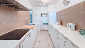 Una cocina moderna con estufa integrada, un lavamanos, un ventilador de techo y un reloj en la pared.