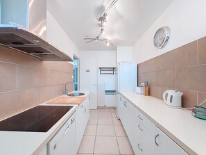 Eine moderne Küche mit Einbauherd, Spüle, Deckenventilator und einer Uhr an der Wand.