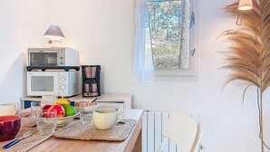 Eine Küche mit Esstisch, verschiedenen Geräten und einem Fenster mit Blick auf Bäume.